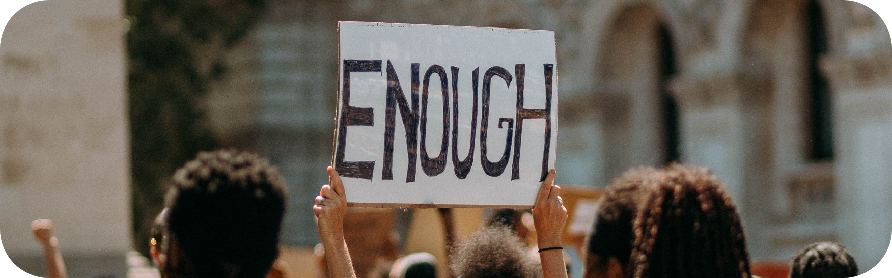 A protest sign help high with the word enough