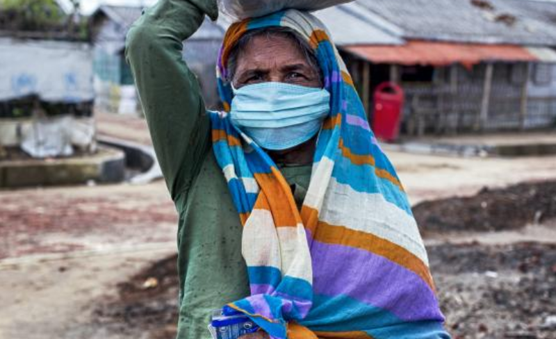 A woman wearing a mask carrying something on her head